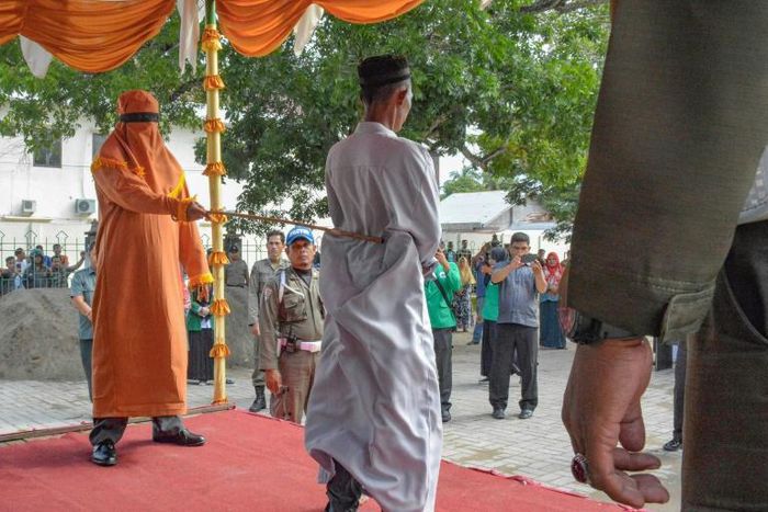 Dozens in the crowd in Indonesia's conservative Muslim province of Aceh jeered and called for the men to be whipped harder