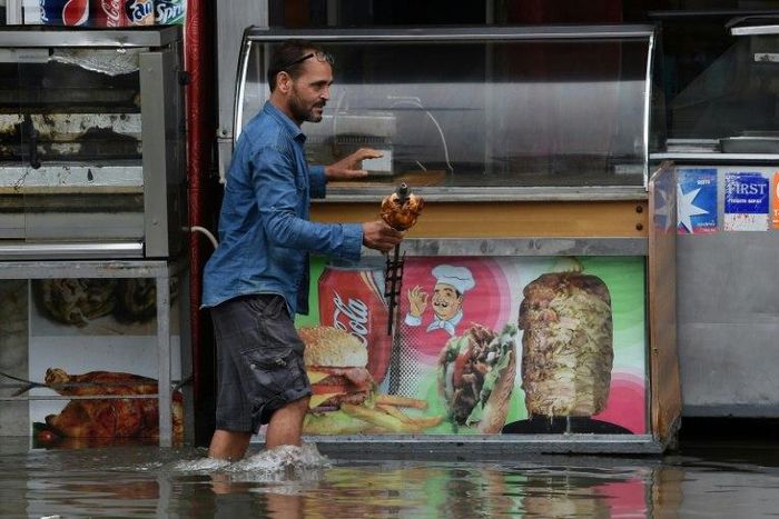 A shop owner tries to salvage his merchandise in a street flooded by torrential rains in the Tunisian capital Tunis on October 18, 2018