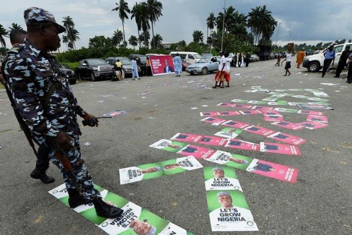 Policemen step on campaign posters of candidates who are jostling for the People's Democratic Party (PDP) presidential nomination ahead of the country's 2019 elections