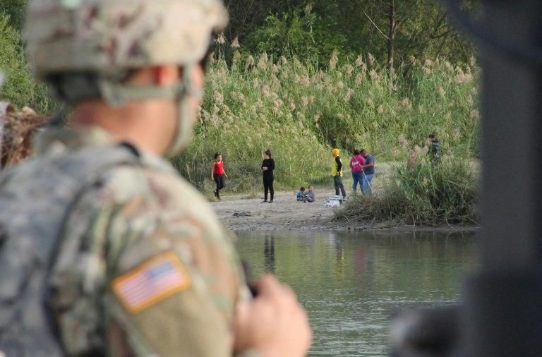 A group of people hang out on the Mexican side of the Rio Grande river, as seen from Laredo, Texas