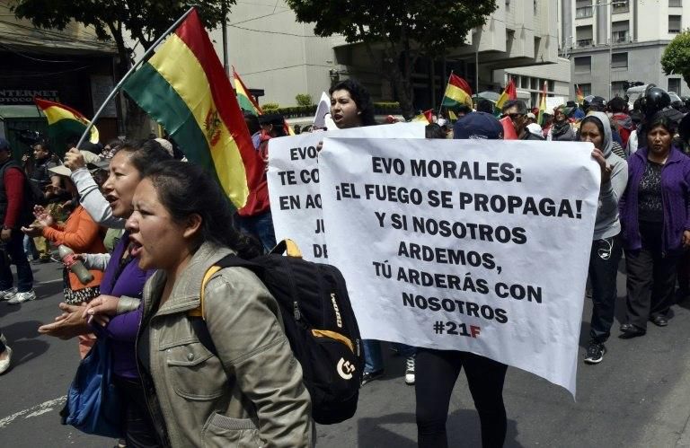 People with a sign reading "Evo Morales: Fire spreads! And if we burn, you will burn with us," march against the nomination of the Bolivian president as candidate for reelection for the October 2019 elections, in La Paz on December 6, 2018