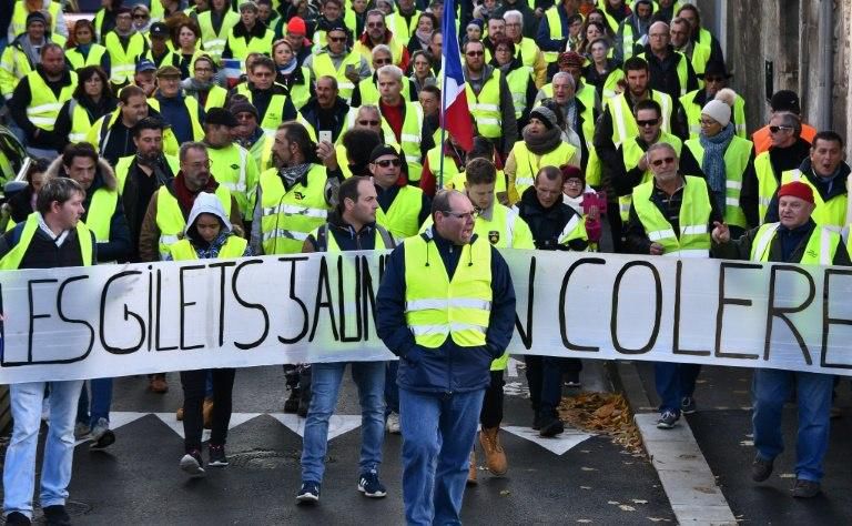 Yellow Vests (Gilets jaunes) march behind a banner reading " Yellow vests are angry" at a protest rally against high fuel prices in Rochefort, southwestern France on Saturday