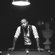 Davido leans against a pool table for his Native magazine shoot