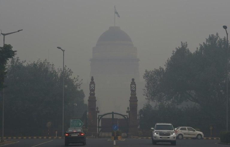 Commuters are seen near the Indian President's house amid heavy smog in New Delhi