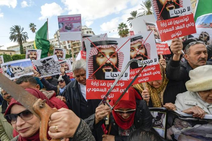 Tunisian women hold up saws and signs saying in Arabic, "No welcome, Tunisians against the visit of the Saudi Crown Prince to Tunisia", during an anti-Saudi Crown Prince protest in Tunis on November 27, 2018