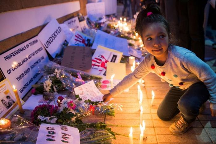 A Moroccan girl places a flower during a vigil for the two Scandinavian hikers, who were killed in Morocco's High Atlas mountains, outside the Danish Embassy in Rabat on December 22, 2018