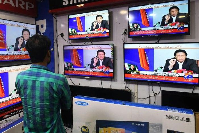 A Pakistani resident watches the speech of Prime Minister Imran Khan, who announced plans to seek a bailout from the International Monetary Fund
