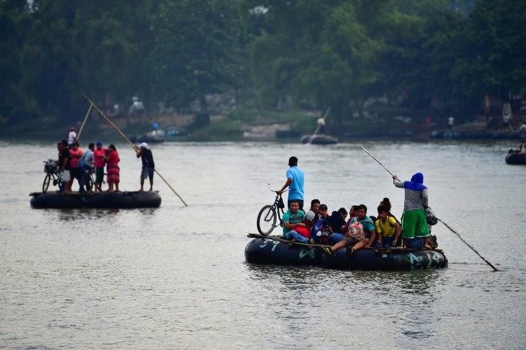 Honduran migrants heading in a caravan to the US use makeshift rafts to cross the Suchiate River which marks the border between Guatemala and Mexico, in Ciudad Hidalgo, Chiapas state, Mexico, on October 20, 2018.