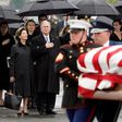 Former US president George W. Bush and former first lady Laura Bush watch as the flag-draped casket of former US president George H.W. Bush is carried to a train for the final journey to his burial place at his presidential library