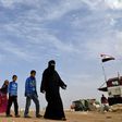 Syrian families walk as members of Russian and Syrian forces stand guard at the Abu Duhur crossing on the eastern edge of Syria's Idlib province on October 23, 2018.Civilians are coming from rebel-held areas in Idlib province and entering regime-held t...