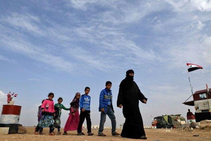 Syrian families walk as members of Russian and Syrian forces stand guard at the Abu Duhur crossing on the eastern edge of Syria's Idlib province on October 23, 2018.Civilians are coming from rebel-held areas in Idlib province and entering regime-held t...