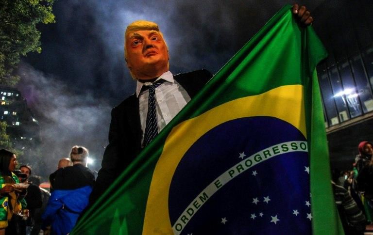 A supporter of Jair Bolsonaro wears a mask of US President Donald Trump, whom Bolsonaro admires, after the Brazilian won his country's presidential election