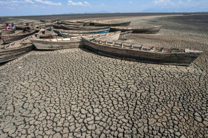 Young men sit in stationary engineless boats which lie idle at the dried inland Lake Chilwa's Chisi Island