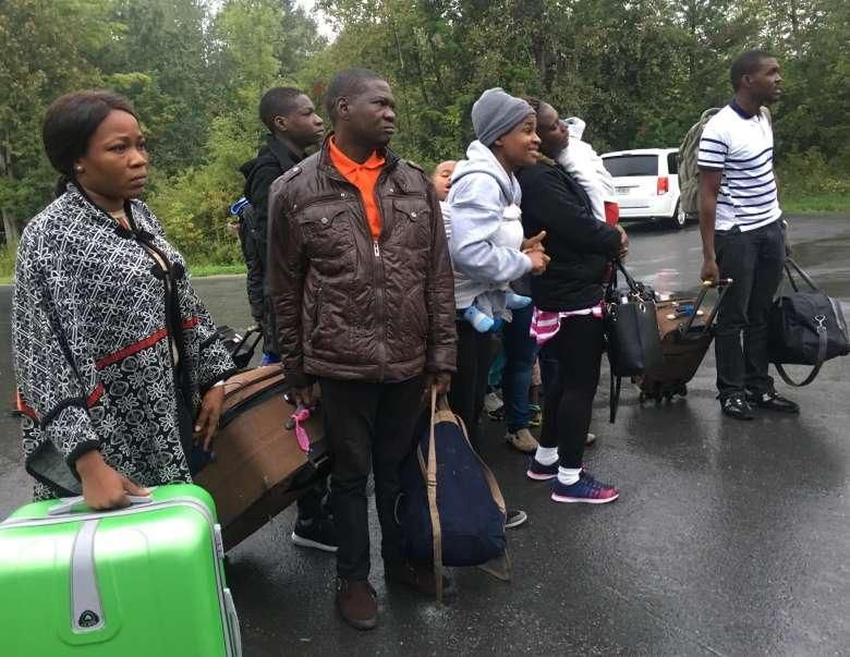 Asylum seekers who are steps away from Canada listen as the Royal Canadian Mounted Police tells them they will be arrested as they cross over from New York state, north of Plattsburgh
