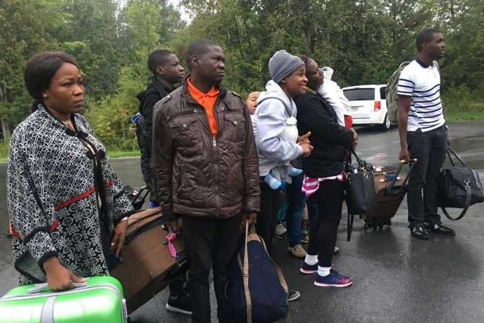 Asylum seekers who are steps away from Canada listen as the Royal Canadian Mounted Police tells them they will be arrested as they cross over from New York state, north of Plattsburgh