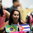 A Cuban doctor retuurns to Havana airport brandishing the flags of her homeland and Brazil, where she was part of a medical aid program