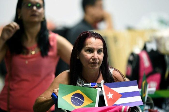 A Cuban doctor retuurns to Havana airport brandishing the flags of her homeland and Brazil, where she was part of a medical aid program