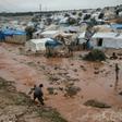 Displaced Syrians walk through a flooded camp near Qah in the northeastern Idlib province on December 27, 2018