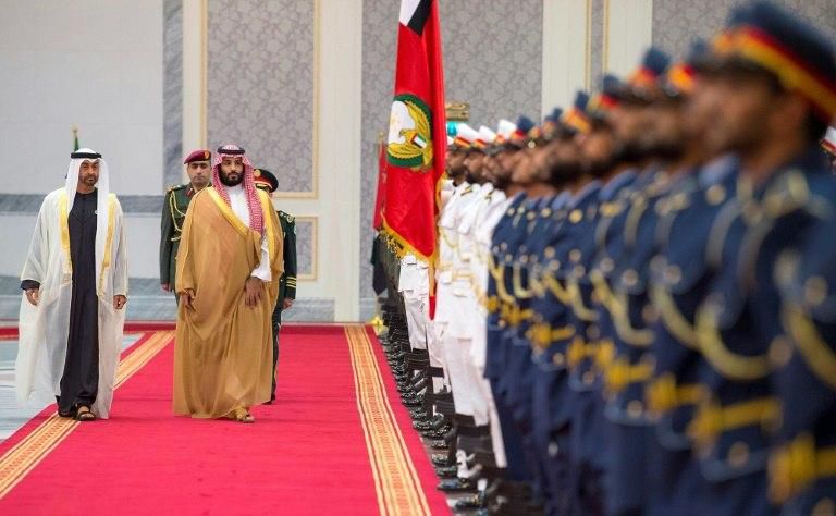 A handout picture provided by the Saudi Royal Palace on November 22, 2018, shows Saudi Crown Prince Mohammed bin Salman (C) and Sheikh Mohamed bin Zayed Al-Nahyan (L), Abu Dhabi's Crown Prince, reviewing an honour guard in Abu Dhabi
