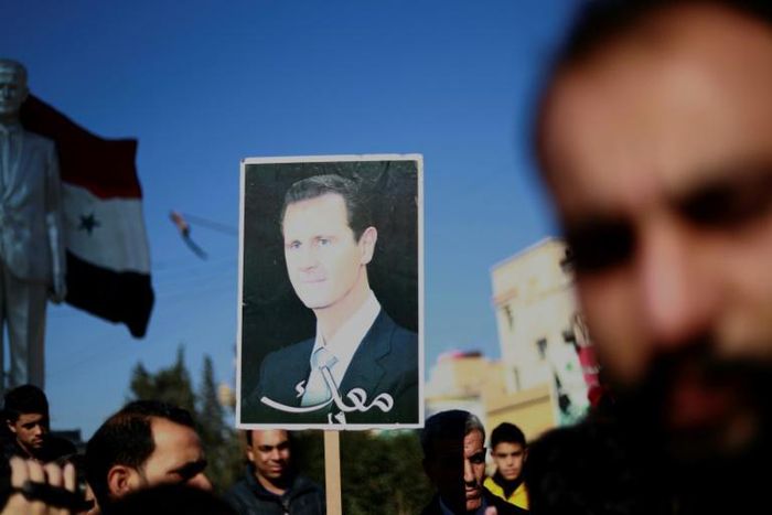 Syrian Kurds hold a portrait of President Bashar al-Assad during a demonstration in the northeastern city of Qamishli on December 23, 2018, seeking protection by the Syrian army against Turkey following a shock US decision to withdraw its troops