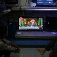 People watch television in an electric goods store in Dhaka as Chief Election Commissioner Nurul Huda addresses the nation on November 8, 2018