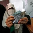 A Palestinian woman counts her money after receiving her salary in Rafah in the southern Gaza Strip on November 9, 2018