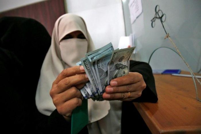 A Palestinian woman counts her money after receiving her salary in Rafah in the southern Gaza Strip on November 9, 2018