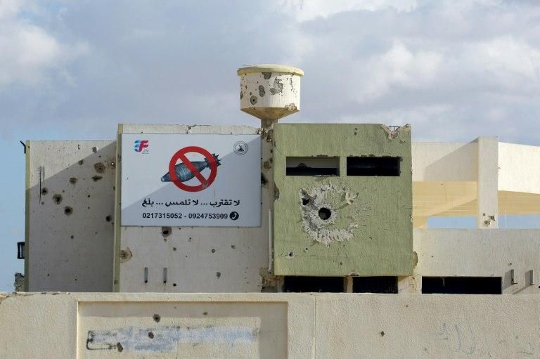 A building in Tawergha damaged by heavy fire, with a sign in Arabic calling for people to stay away from unexploded devices