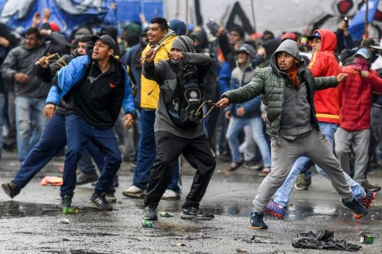 Demonstrators use slingshots to fire rocks at riot police outside Argentina's Congress in Buenos Aires -- unrest that preceded the vote on the austerity measures