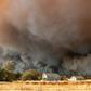 In this photo taken on November 8, 2018 a home is overshadowed by towering smoke plumes as the Camp fire races through town in Paradise, California