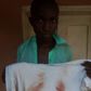 A student holds out a white with blood stains. He reportedly bled into it after receiving mighty whips in school.
