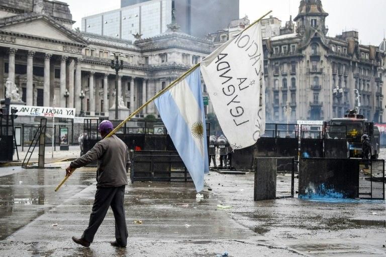 A protester carries the Argentine flag outside the Congress -- Buenos Aires is trying to cut Argentina's fiscal deficit and tame inflation at the IMF's behest