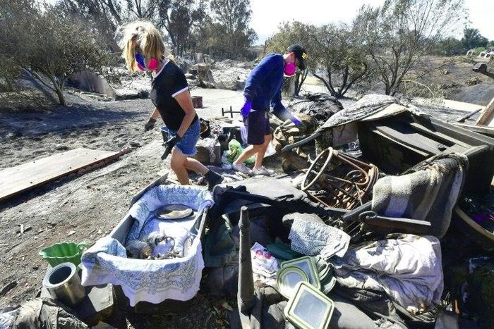 Katherine Marinara and her son Luca sift through the remains of their home in Malibu, California