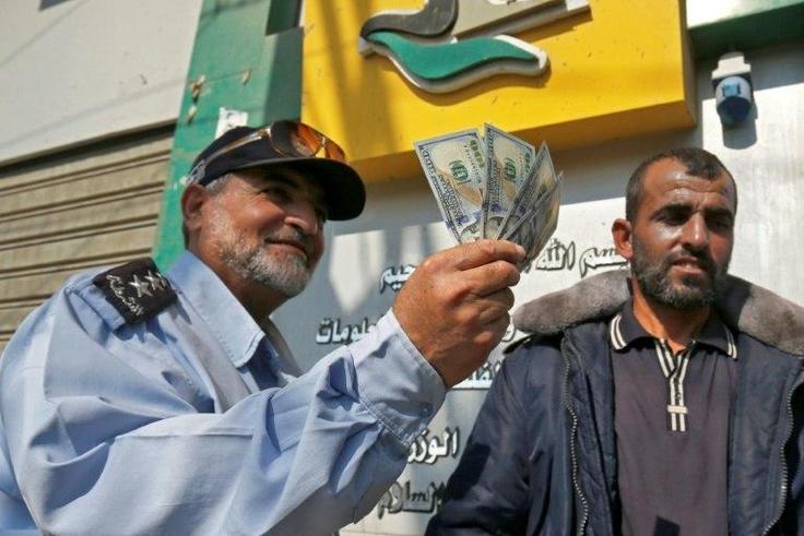 A Palestinian man shows his money after receiving his salary in Rafah in the southern Gaza Strip November 9, 2018