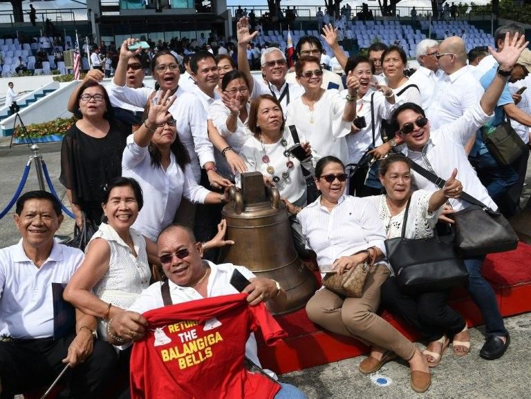 Residents from Balangiga town pose for photos next to one of the three Balangiga church bells shortly after it arrived