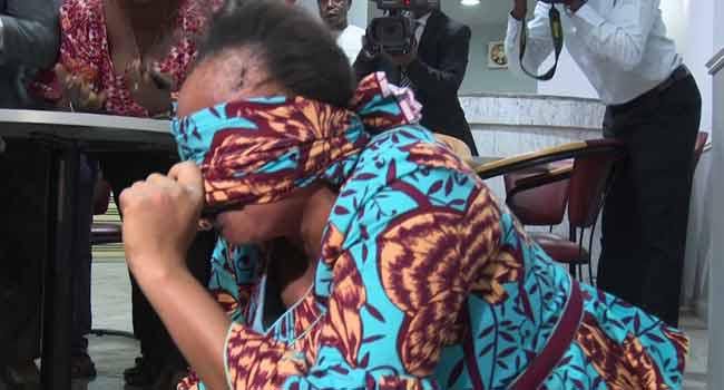 Amina Mohammed attempts to shield her face from the camera