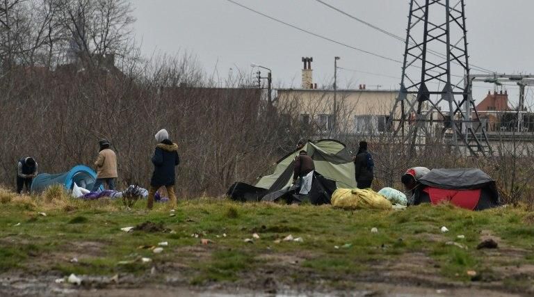 Migrants set up tents on muddy wasteland near the port of Calais