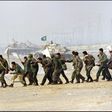 Iraqi soldiers cross a highway carrying white surrender flags 25 February 1991 in Kuwait City