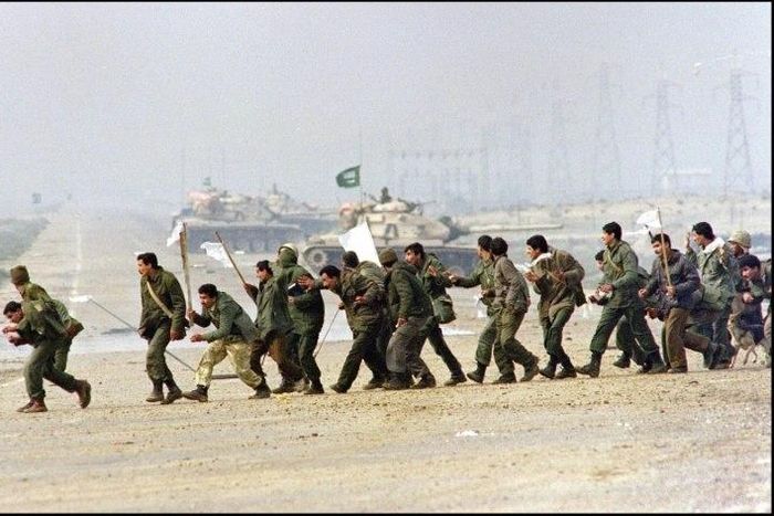 Iraqi soldiers cross a highway carrying white surrender flags 25 February 1991 in Kuwait City