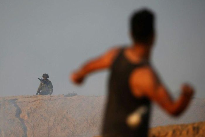 A Palestinian protestor throws a stone towards Israeli forces near the maritime border with Israel in the northern Gaza Strip, during a demonstration calling for the end of the Israeli blockade on September 10, 2018