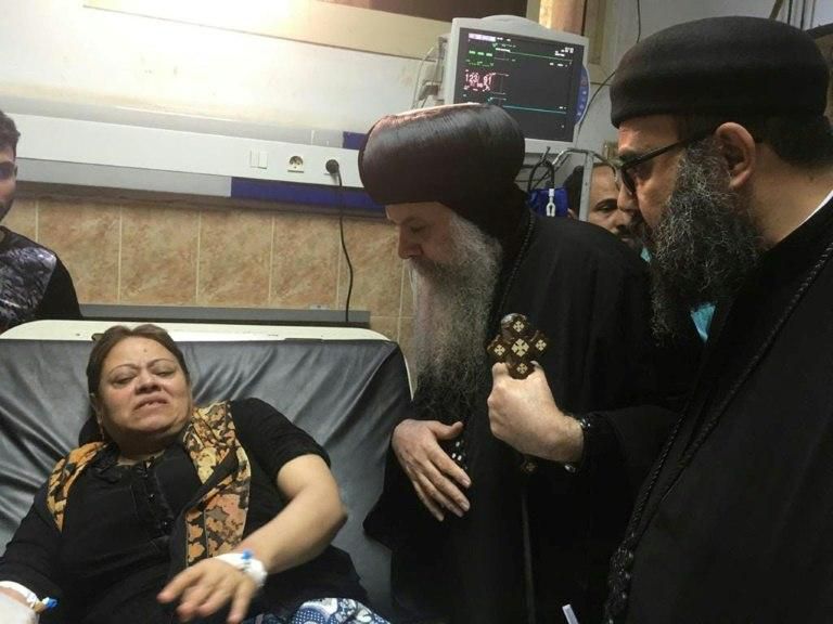 An Egyptian Coptic priest speaks to a woman wounded when gunmen attacked a bus carrying Coptic Christians on November 2, 2018
