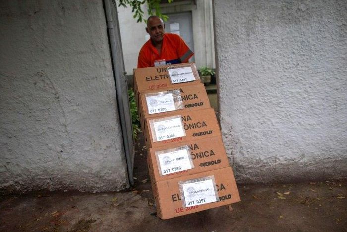 A worker at the Regional Electoral Court Storage in Jardim Botanico neighborhood, Rio de Janeiro, carries electronic ballots for distribution during preparations on the eve of Brazil's general election