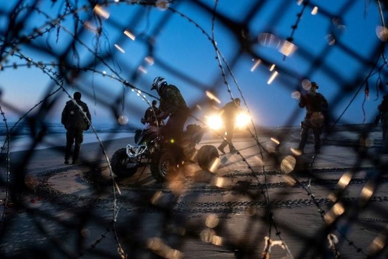 Border patrol agents look on after migrants traveling in the Central American Caravan crossed through the Mexico-US border fence from Tijuana to San Diego County, as seen from Playas de Tijuana, Baja California state, Mexico