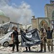 In this file photo taken on June 30, 2017 a member of Iraq's counter-terrorism squad flashes a victory sign as others hold upside-down an Islamic State group flag outside Al-Nuri Mosque in Mosul's Old City after IS was ousted from the area