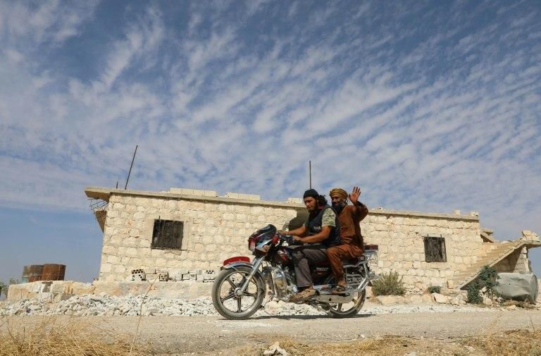 Rebel fighters ride a motorcycle in the area of Al-Eis in northern Syria on October 7, 2018