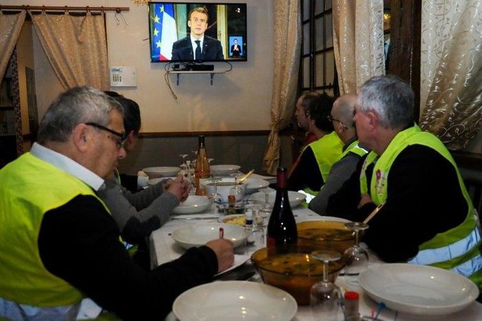 'Yellow vest' protestors take notes as they watch French President Emmanuel Macron's speech on television