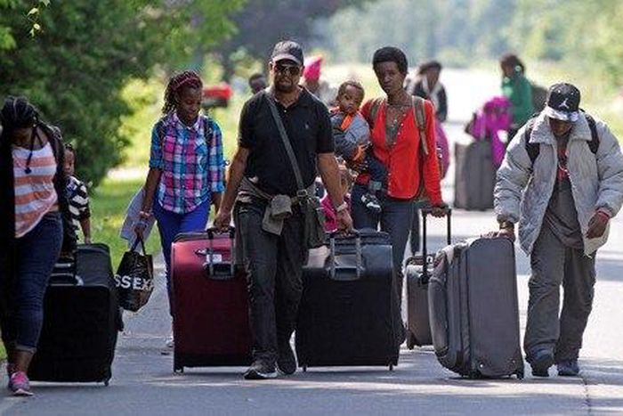 Asylum seekers walk down Roxham Road to cross into Quebec at the U.S.-Canada border in 2017