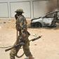 A Somali soldier patrols next to the burnt-out wreckage of a car that was used by suspected Al-Shabab fighters, which increasingly have been targeted by the US military