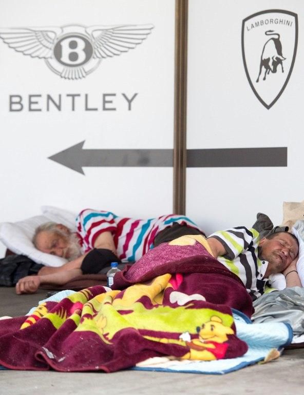Wealth and poverty: homeless people in San Francisco asleep under the logos of the world's most expensive cars