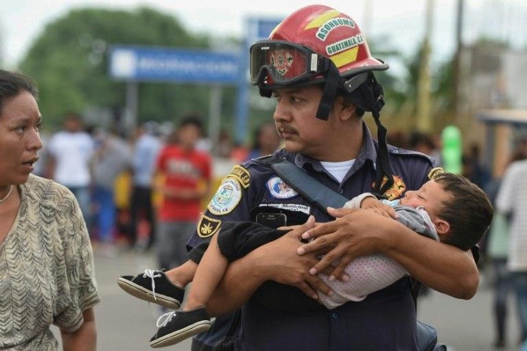 A Guatemalan firefighter carries an ailing baby, as an Honduran migrant caravan heading to the US, reaches the Guatemala-Mexico international bridge in Tecun Uman, Guatemala on October 19, 2018.